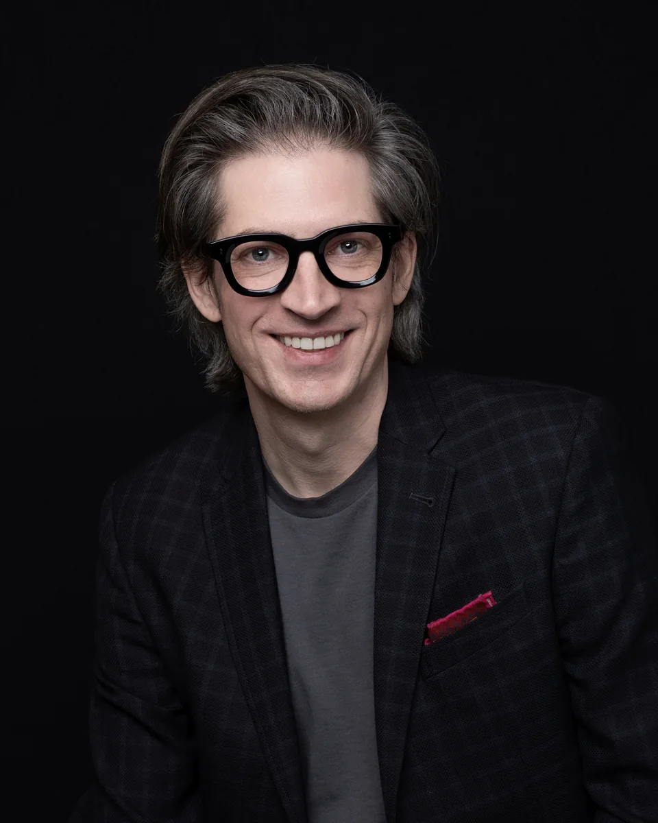 Jake Miller in a dark jacket, a portrait of the founder and assurance-minded technologist behind Pink Stack Studio.